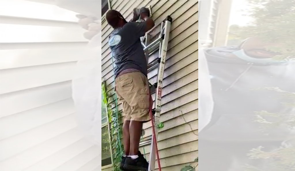 Employee and owner James Green on a ladder that is leaned up against the house while cleaning a dryer vent in Wauwatosa.