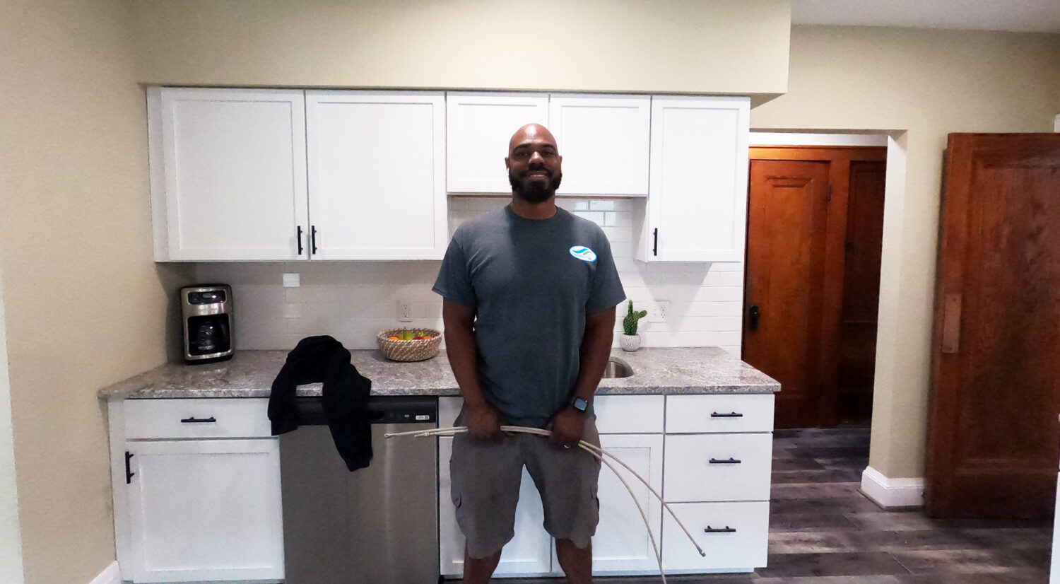 Owner Operator, James Green standing in front of kitchen cabinets, smiling and holding an air duct cleaning tool.
