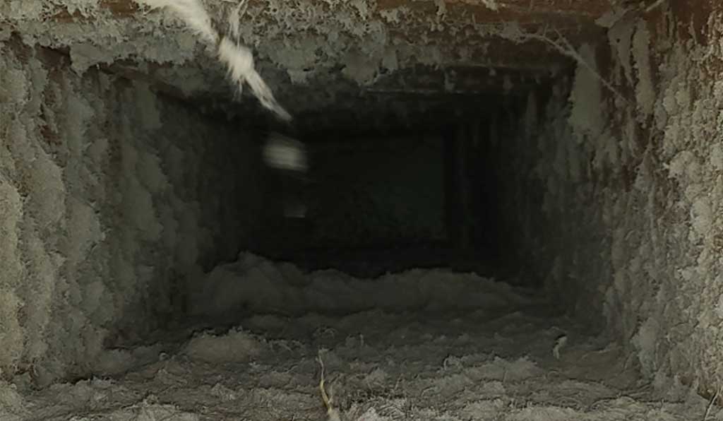 Disgusting sheet metal air duct with debris built up on walls of enclosure in bayside.