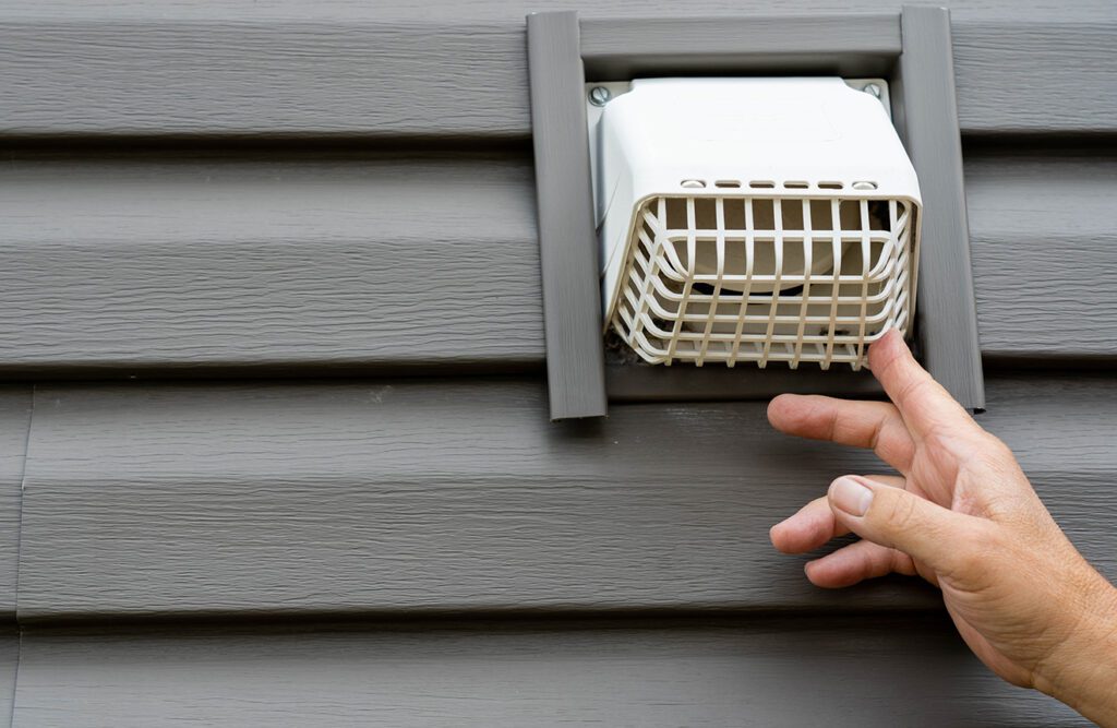 white plastic dryer vent on the exterior of a home