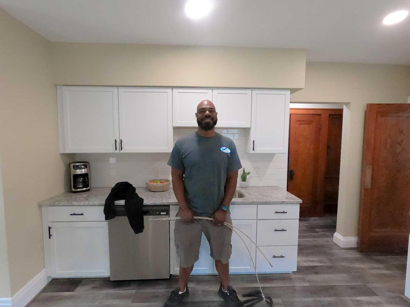 Owner Operator, James Green standing in front of kitchen cabinets, smiling and holding an air duct cleaning tool.