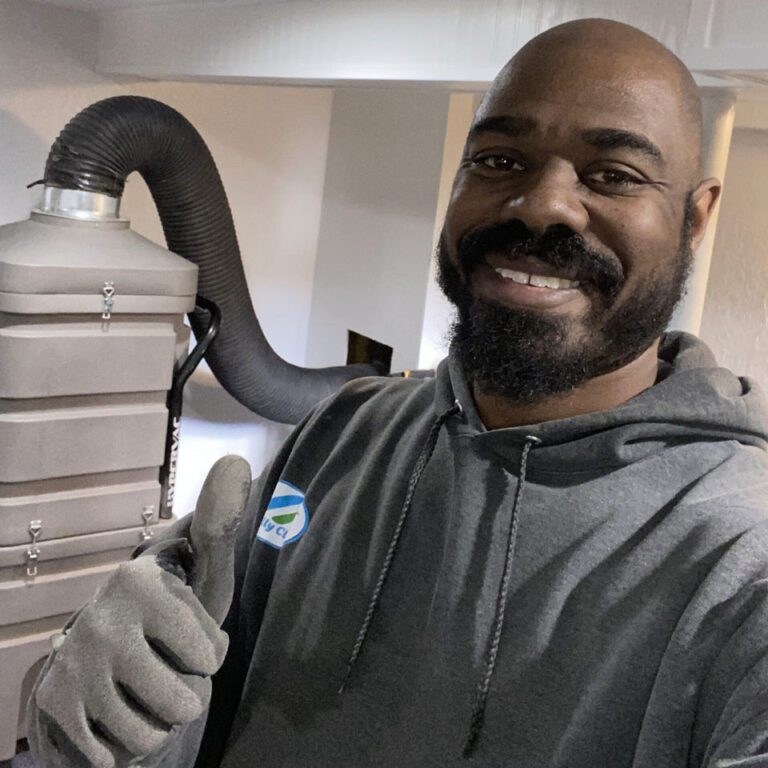 Totally Clean Owner posing next to a vent cleaning vacuum on the job.