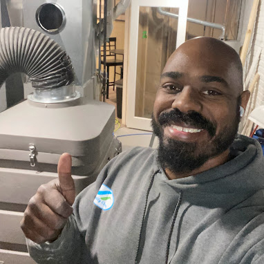 Owner of Totally Clean smiling next to a furnace plugged into commercial air ducts.