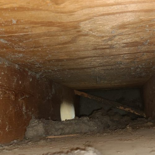 Return ducting with drywall chunks and dust covered on the walls and base of venting.